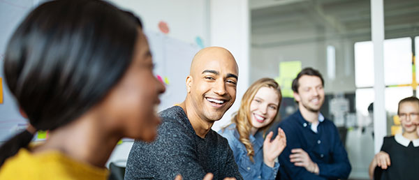 A group of adult students smiles and laughs in class.