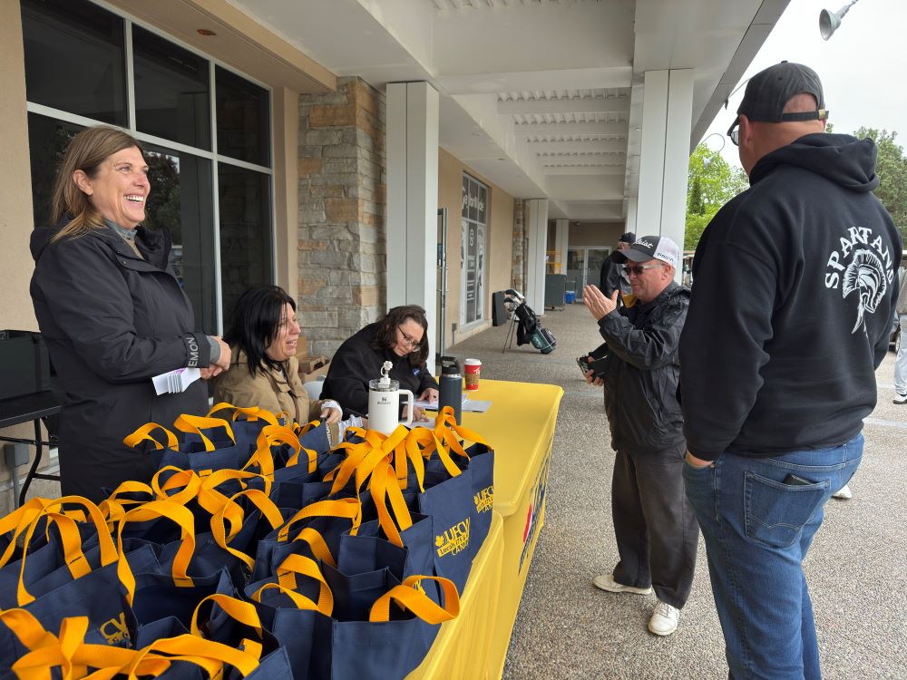 President Kelly Tosato smiles at the registration table during the Locals annual golf tournament 2025.