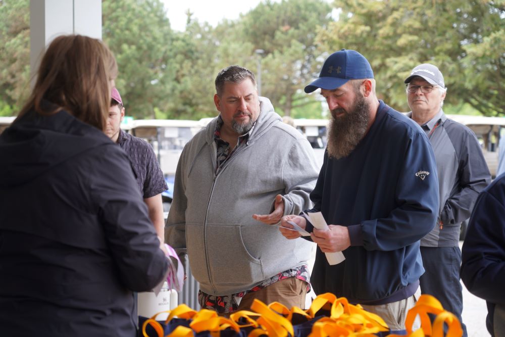 President Kelly Tosato talks to participants at the registration table during the Locals annual golf tournament 2025.
