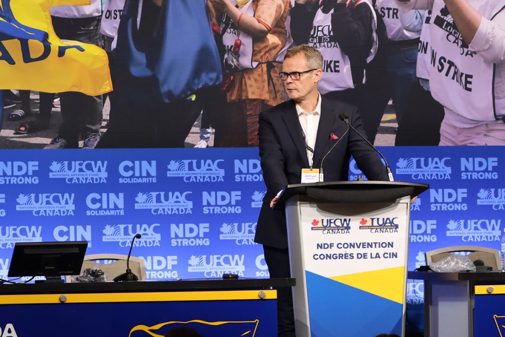 Kristjan Bragason speaks at the podium on stage