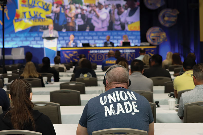 Focus on a person's shirt that reads Union Made with audience and speaker in background at the NDF Convention 2025