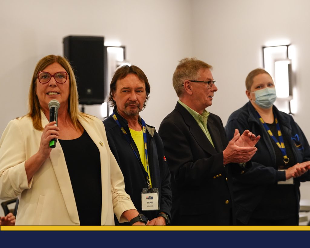 Local 175 President Tosato speaks into the mic with Local 633 Brian Kozlowski, Local 175 Secretary-Treasurer Jim Mclean and Local 633 Secretary-Treasurer Julie MacCrae standing by her