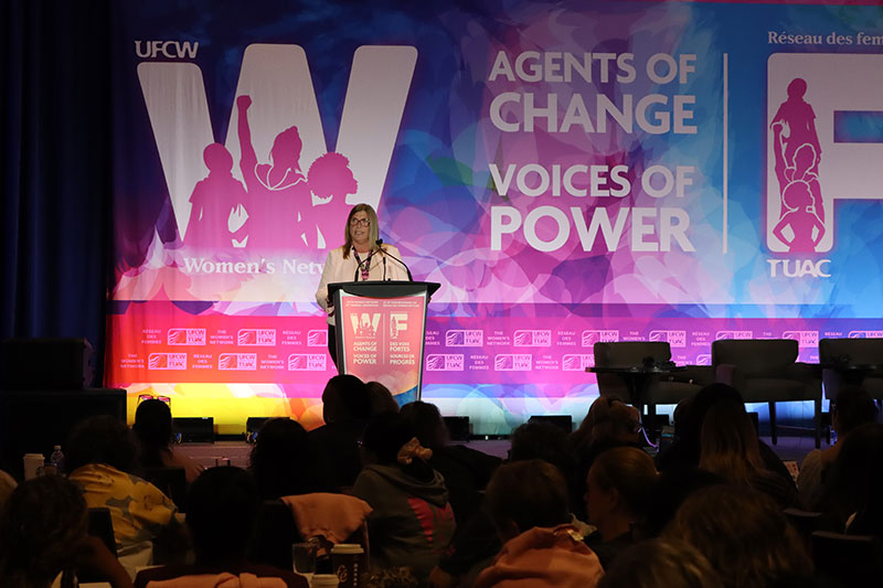 President Kelly Tosato speaks at the microphone on stage
