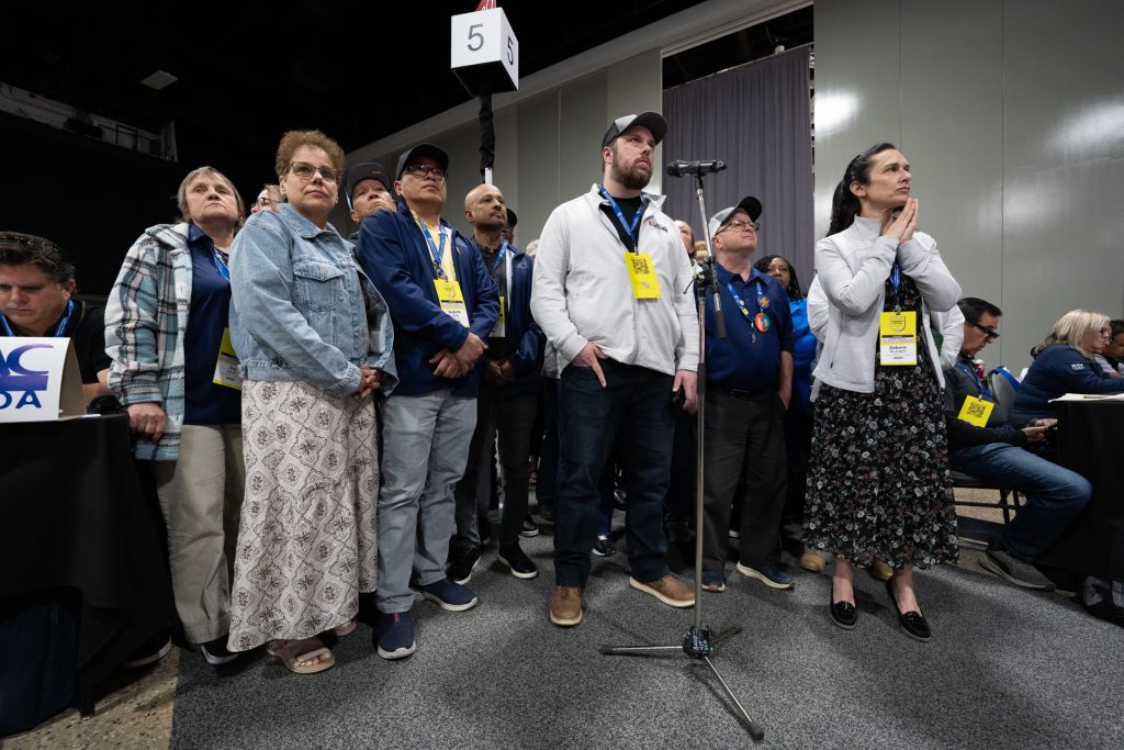 A group of UFCW delegates stand at a microphone