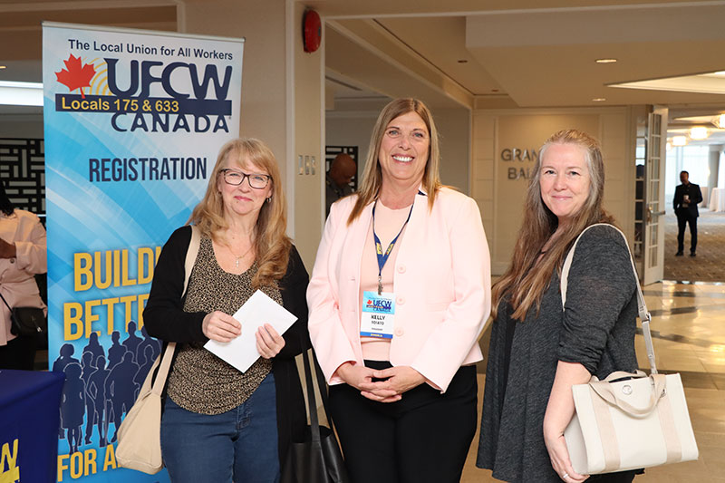 President Tosato stands with two union stewards in front of a union banner; all 3 people are smiling