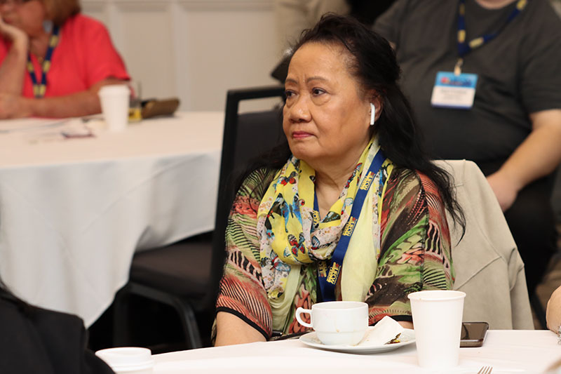 focus on a person sitting at a banquet table as they listen to speakers