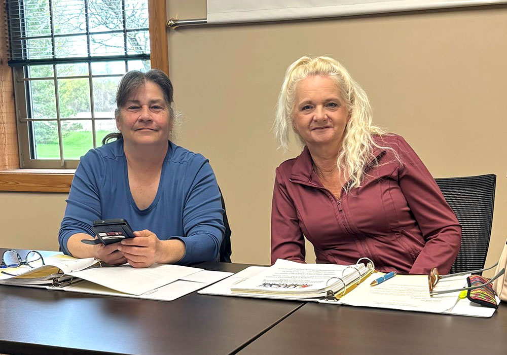 two people seated with binders on the table containing the Caressant Care Harrison collective agreement