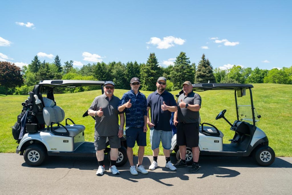 The UFCW Locals 175 & 633 participants smiling for a picture between their two golf carts.