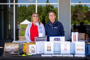 President Kelly Tosato and Secretary Treasurer Jim McLean smile in front of the raffle ticket booth.
