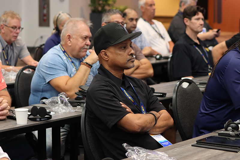 a person with their arms folded sits among other delegates at the NDF Convention