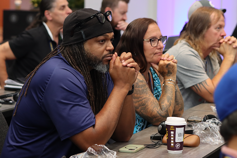 focus on two people seated with their chins resting on folded hands in the audience at the 2026 NDF Convention