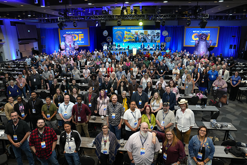 A wide shot of the NDF Convention hall with 200-300 people standing in a group