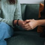 A healthcare worker holds a patient's hand.