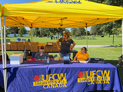President Kelly Tosato and 2 people, one dressed as Rosie the Riveter, under a UFCW tent in Cornwall