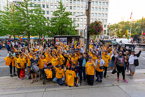 large group of ufcw members in logo t-shirts raising their fists in solidarity standing on the street in Toronto