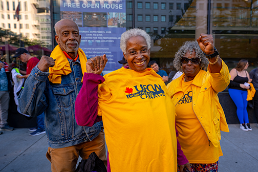 3 people hold up their fists in solidarity while showing off their yellow ufcw shirts
