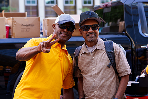2 people posing for a photo; 1 of them is giving the peace sign