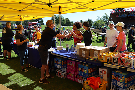 Secretary-Treasurer Jim McLean hands out beverages to several people; other UFCW staff stand behind a table while people line up for a bbq
