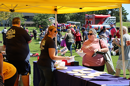 two ufcw staff prepare food for a person at the UFCW tent in Cornwall
