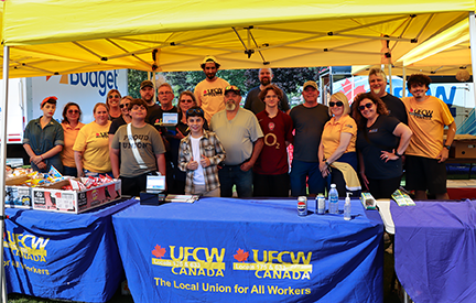 19 people in a group photo next to UFCW tables at the Cornwall Labour Day BBQ