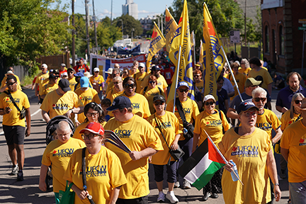 a group of more than 50 people, all in ufcw gear, march in the hamilton labour day parade