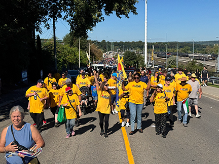 several people at the front of the UFCW parade contingent raise their arms as they march together