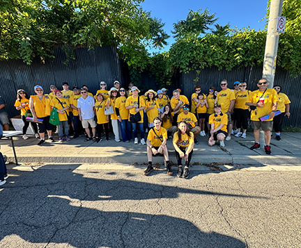 a large group photo featuring about 30 people, most in yellow ufcw shirts, on the sidewalk of the parade staging area