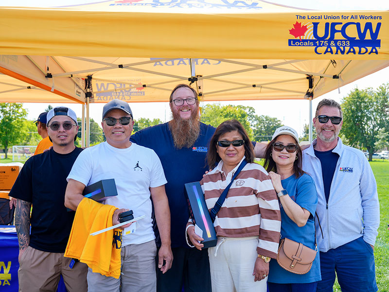 6 people stand in front of a ufcw tent for a group photo at the London Labour Day event