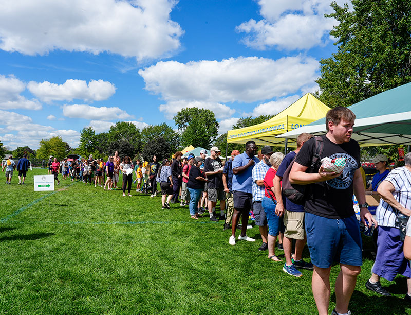Blue skies and green grass as well over 50 people line up for the barbecue in London